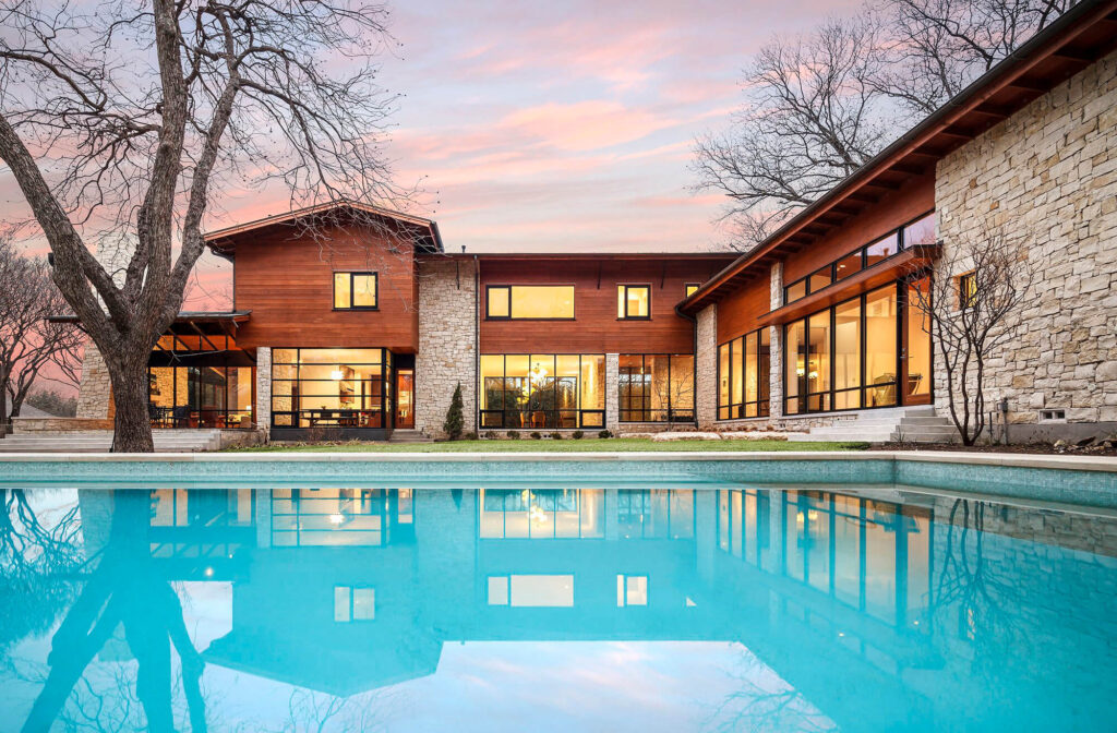 Contemporary custom home exterior with stone wall and wood accents at sunset in Dallas, TX