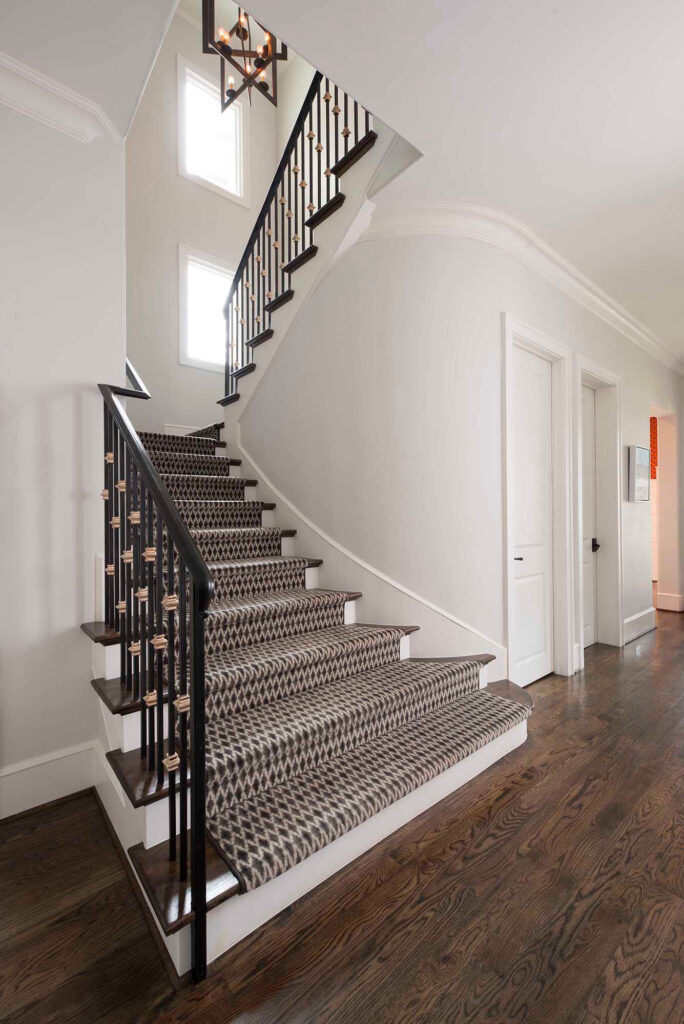 Staircase with black iron railing and runner in luxury Dallas home