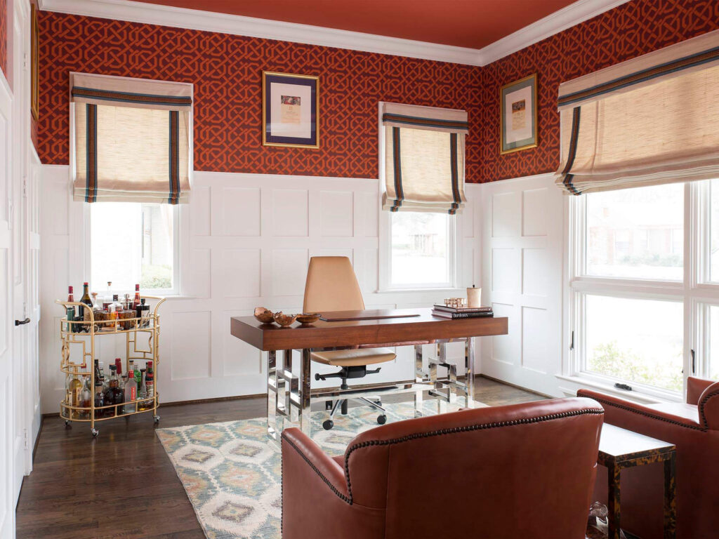 Home office with red patterned wallpaper and wainscoting in Dallas custom home