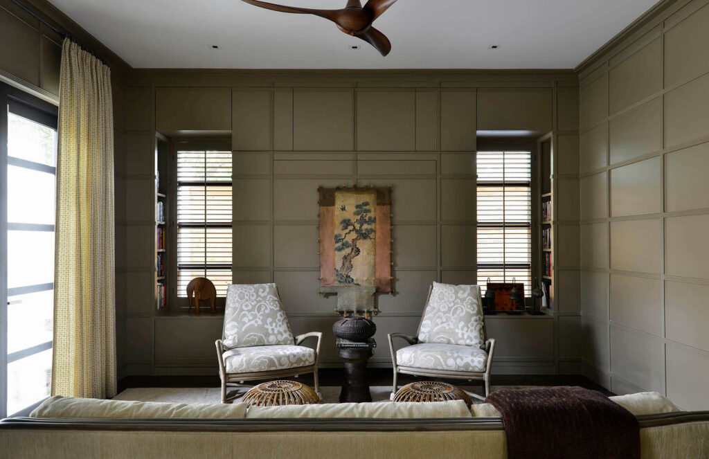 Moody study with paneled walls and built-in shelving in Dallas luxury home