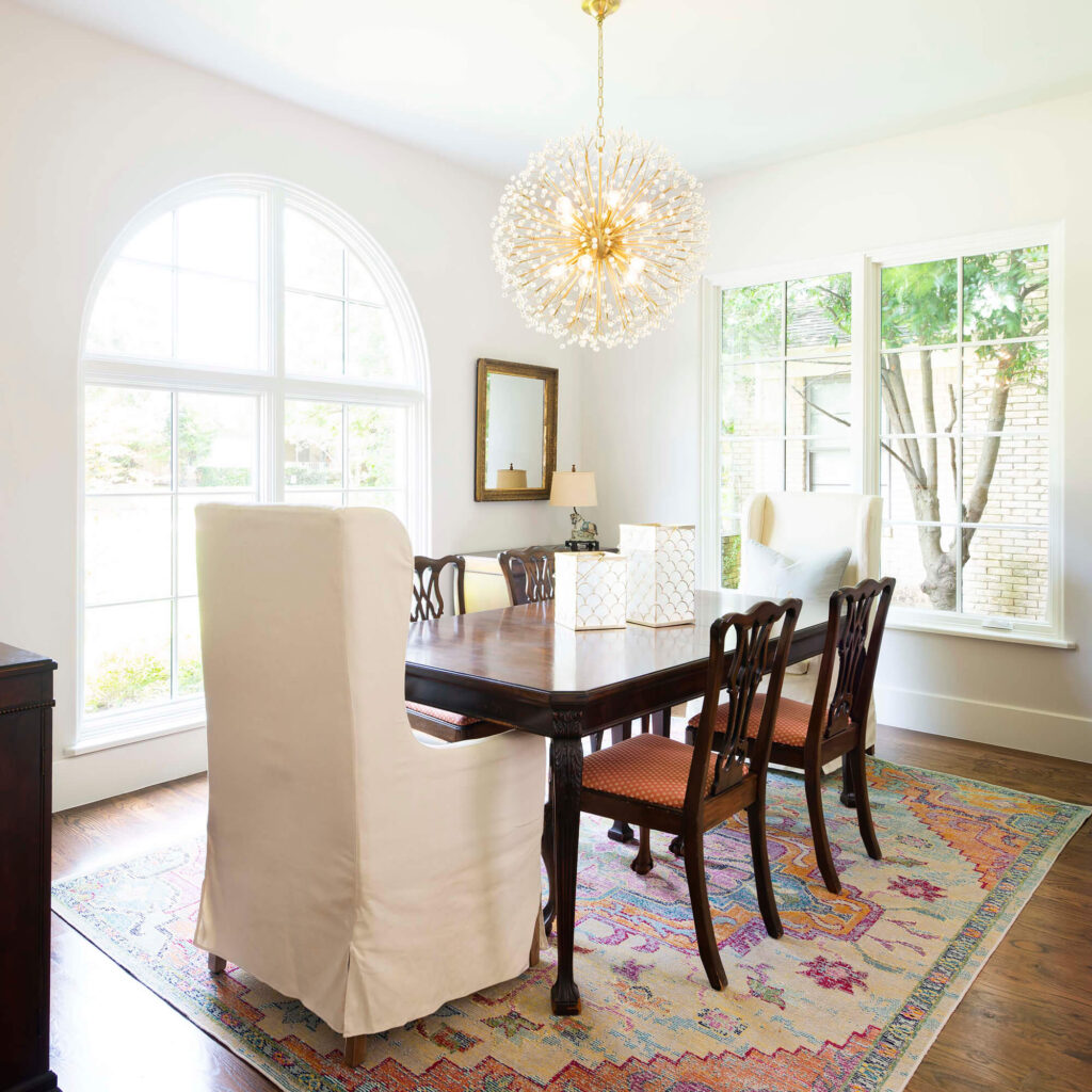 Bright dining area with arched window and statement chandelier in Dallas custom home