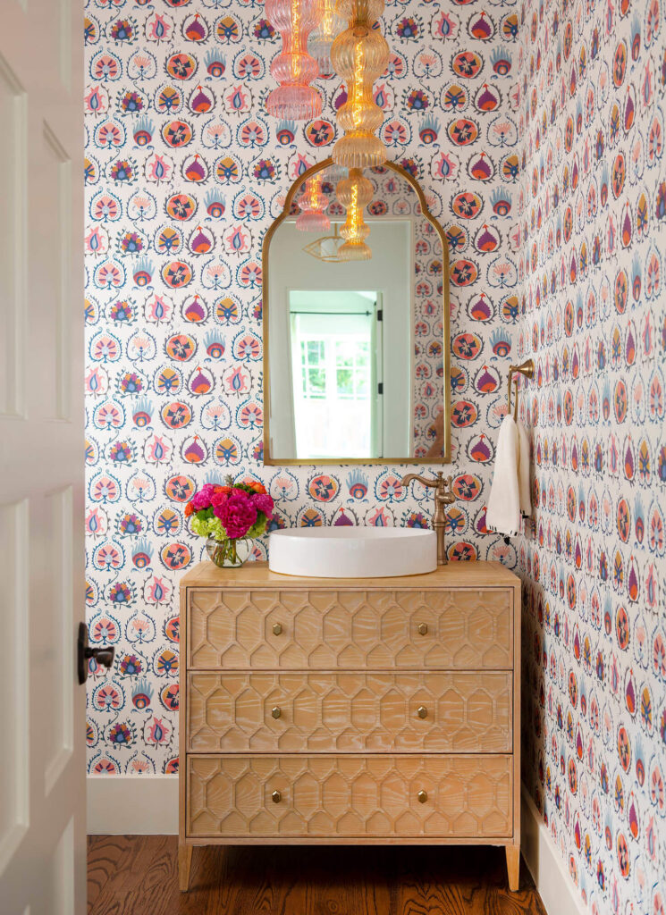 Powder bathroom with patterned wallpaper and arched mirror in luxury custom home in Dallas, TX