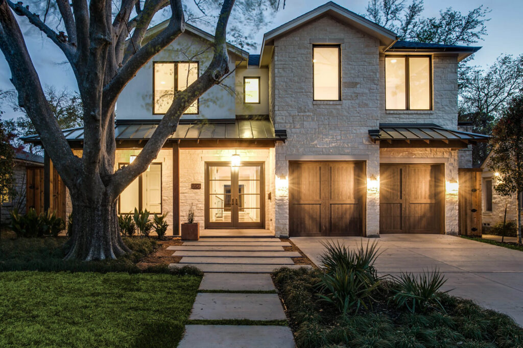 Modern custom home exterior at dusk with warm interior lighting in Dallas, TX