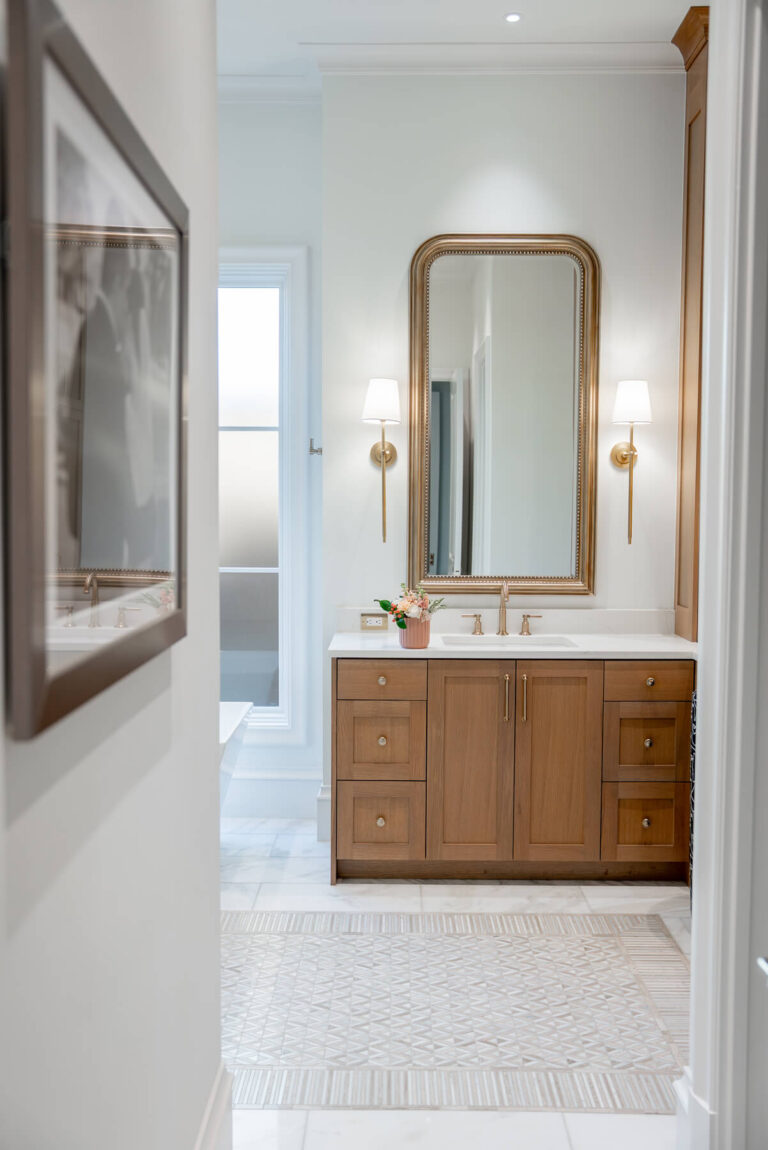 Brunswick primary bathroom vanity with wood cabinetry and brass fixtures in Dallas