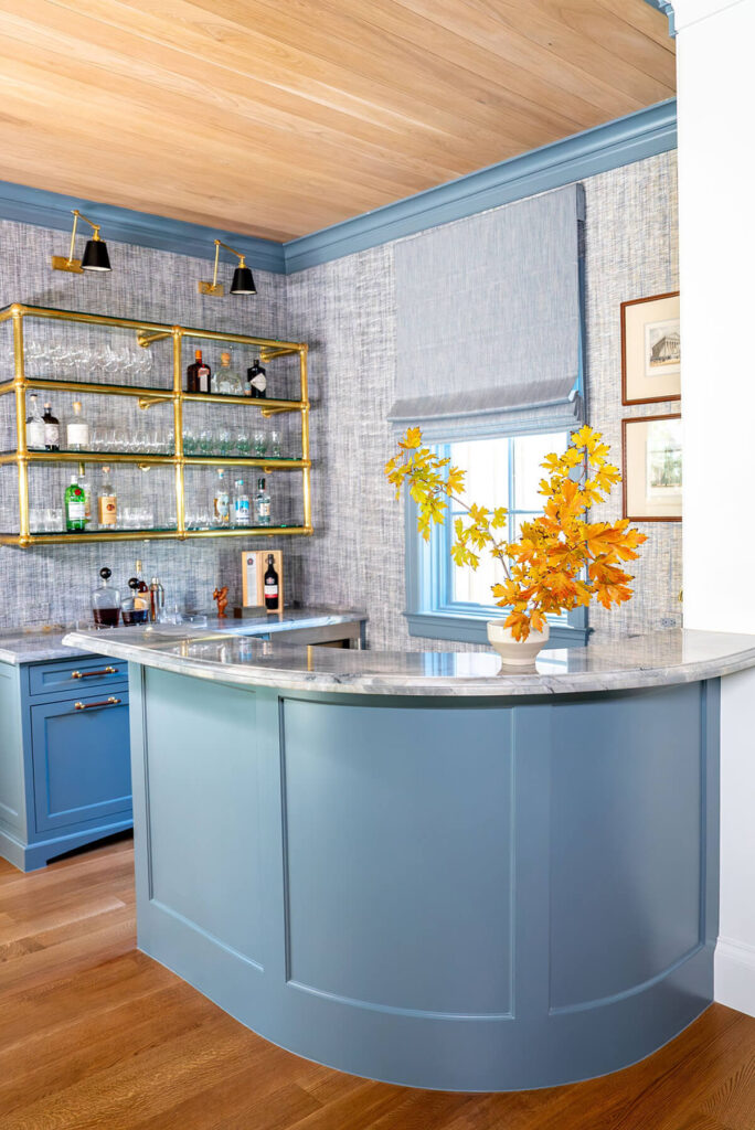 Blue curved custom bar cabinetry with brass shelving detail