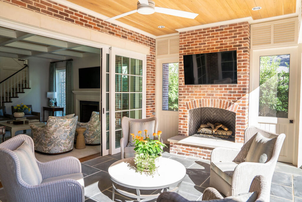 Covered brick patio with fireplace and wood ceiling in Dallas custom home