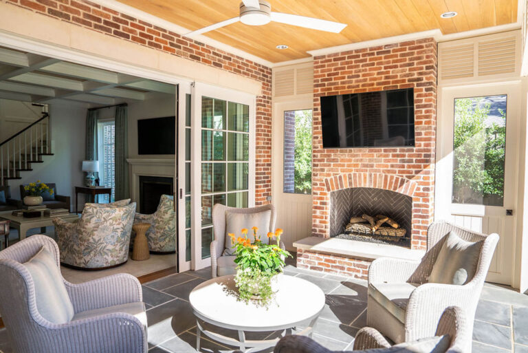 Covered brick patio with fireplace and wood ceiling in Dallas custom home