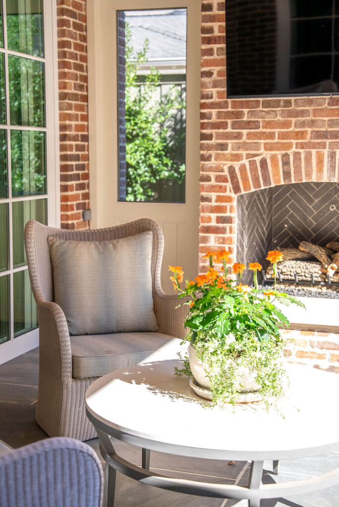 Outdoor brick fireplace seating area with wicker chairs