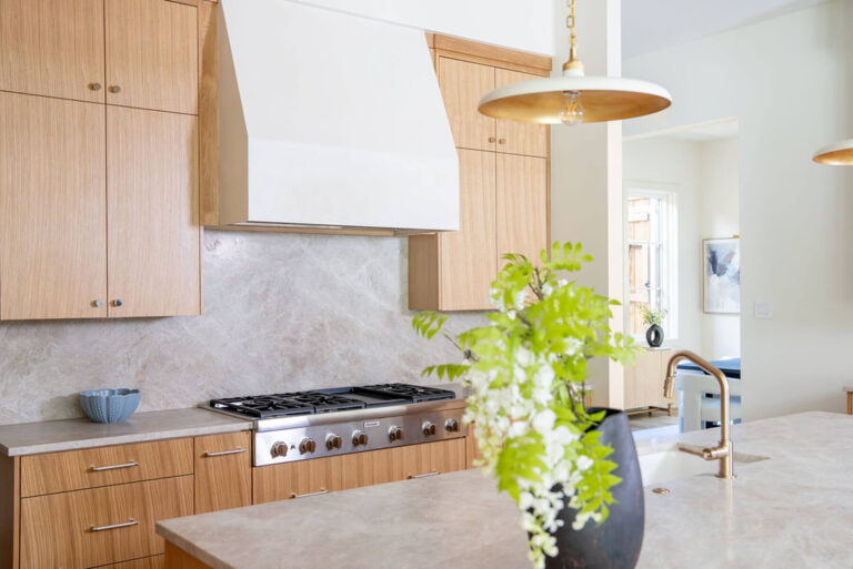 Lyre Lane custom kitchen range wall with white hood and wood cabinetry in Dallas