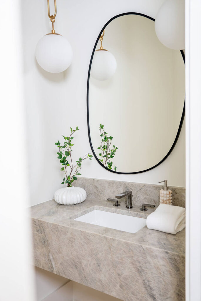 Lyre Lane powder bath with round mirror and stone vanity in Dallas custom home