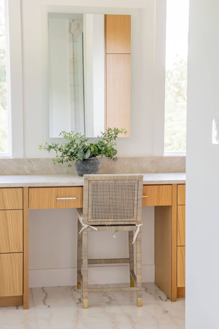 Lyre Lane bathroom vanity detail with woven chair and wood cabinetry in Dallas custom home