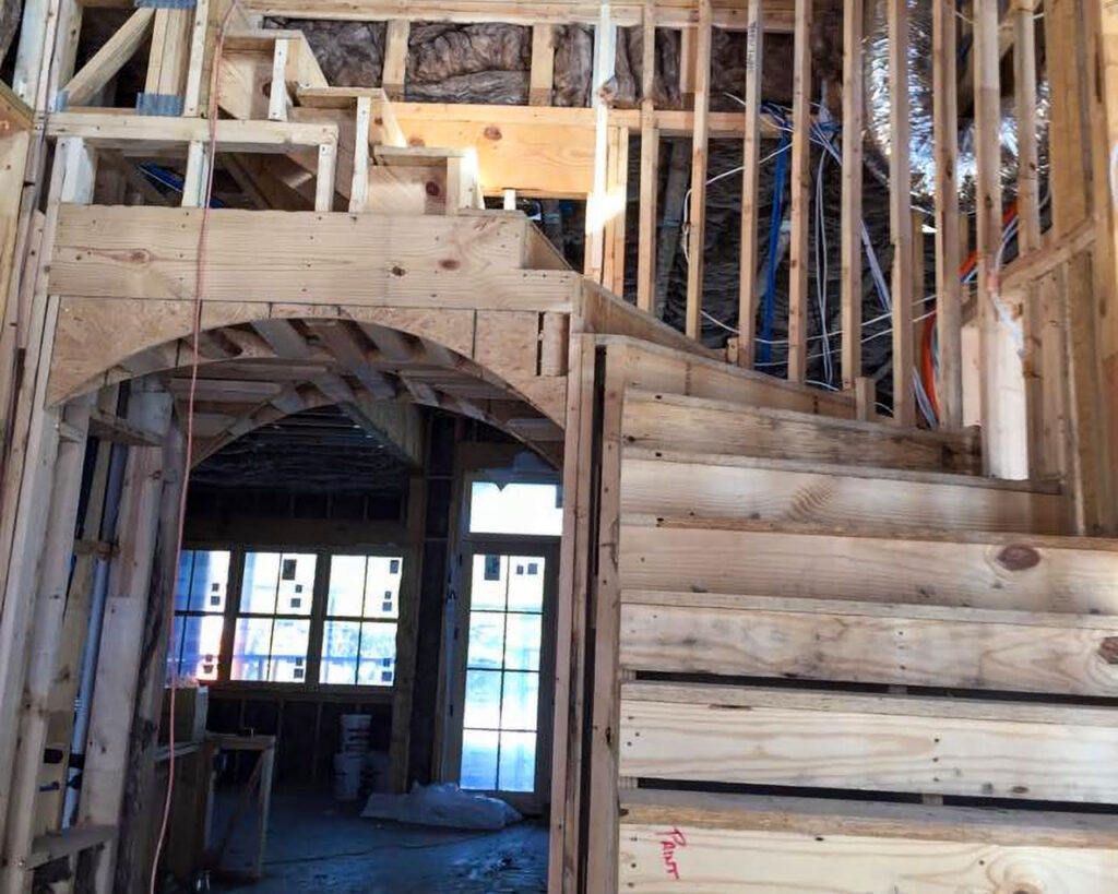 Custom home construction framing with exposed wood beams and staircase structure