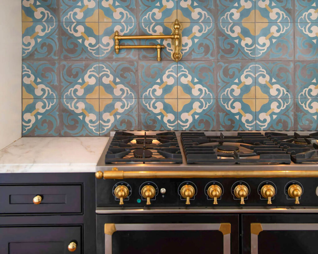 Custom kitchen range with brass hardware and patterned blue tile backsplash in luxury home