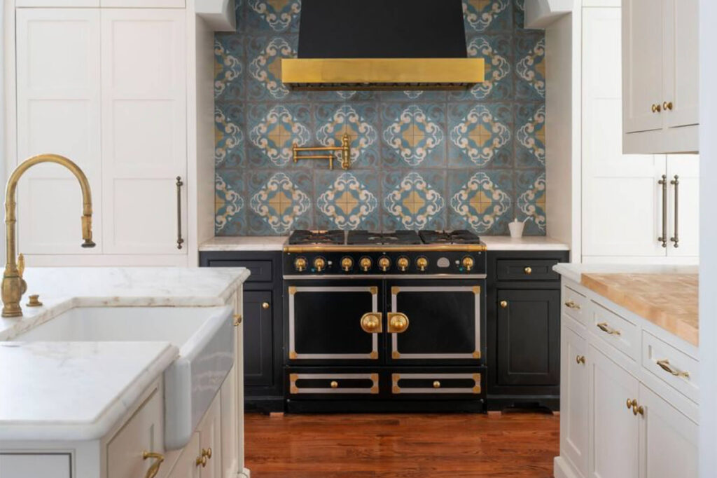 Luxury custom kitchen with patterned tile backsplash, brass vent hood, and professional range
